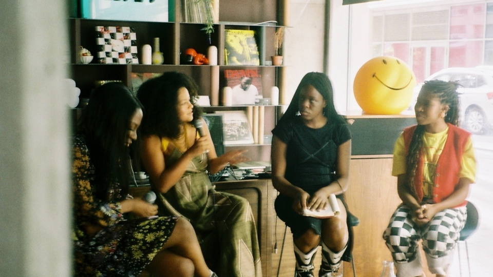 A panel discussion with 4 women of colour. They are sitting on high stools.